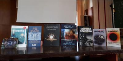 Na stole stoją książki popularnonaukowe, głównie Stephena Hawkinga.