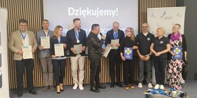 Laureaci konkursu stojący w rzędzie pod ścianą